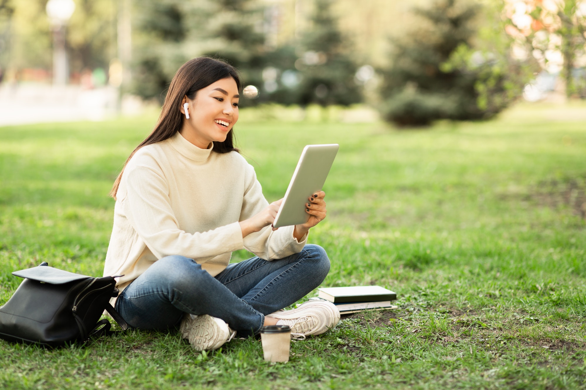 Student using tablet, sitting in the park